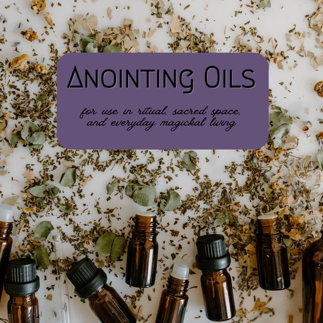 dried herbs scattered across a white surface with a row of amber glass vials along the bottom and a purple box with black text reading "anointing oils, for use in ritual, sacred space, and everyday magickal living"