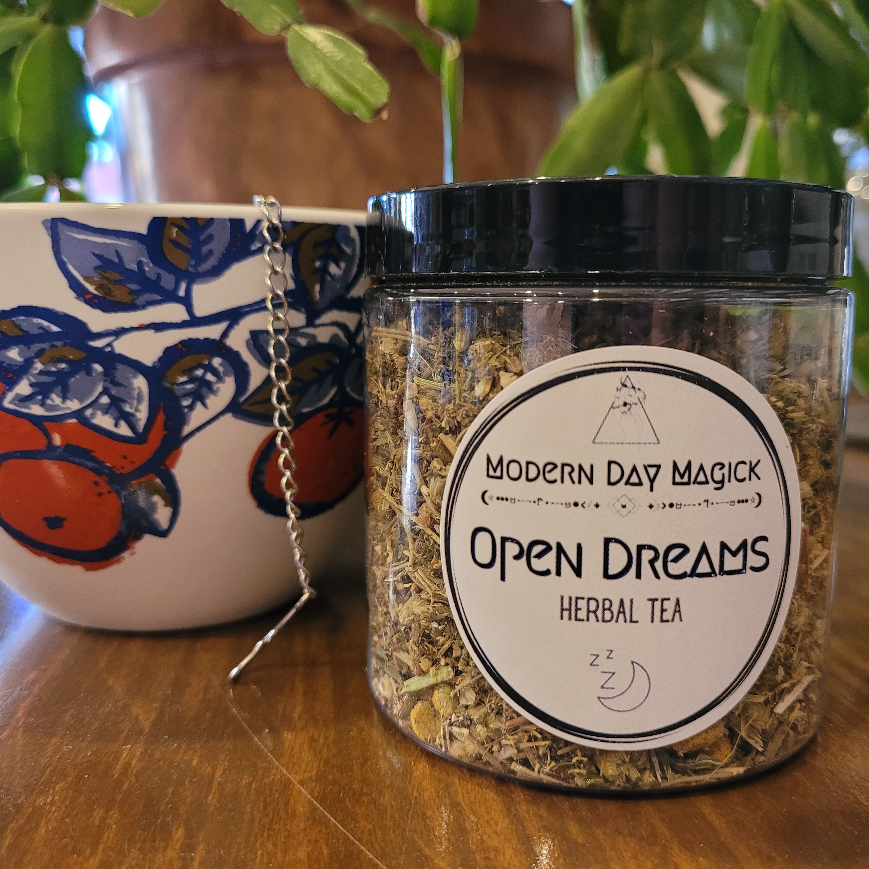 container of loose herbal tea blend made for sleeptime and dreaming, paired with a botanical pattern tea mug and gemstone tea infuser